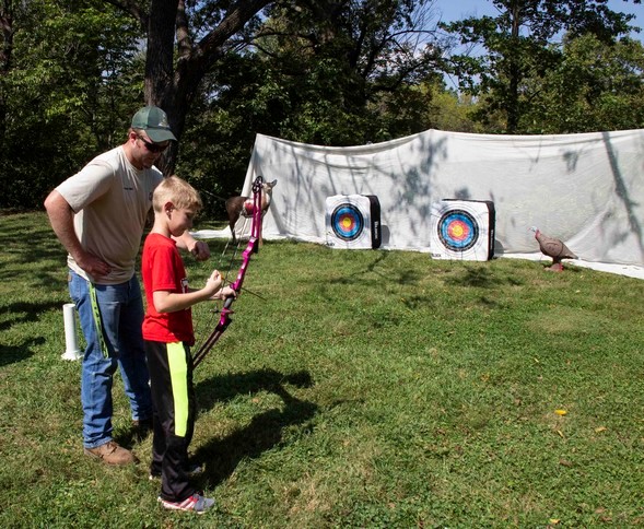 guy teaching archery to kid
