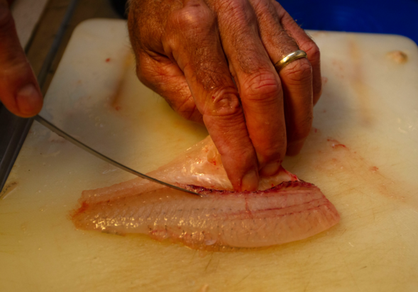 Man cuts fish filets on cutting board