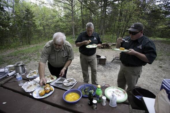 Three MDC staff members eat food after campfire cooking