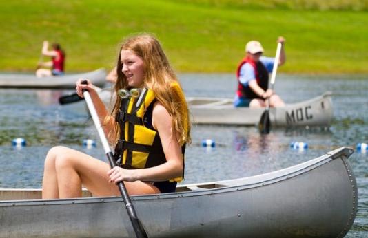 Girl canoes on lake during Girls Camp
