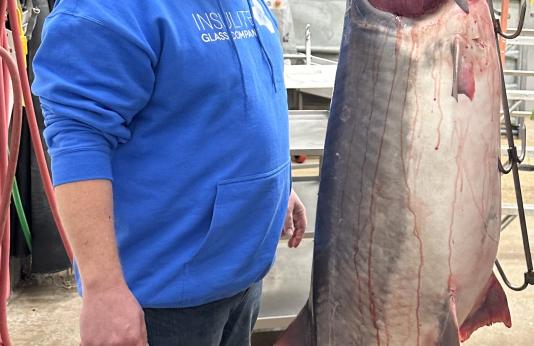 Chad Williams stands next to world record 164-pound, 13-ounce paddlefish